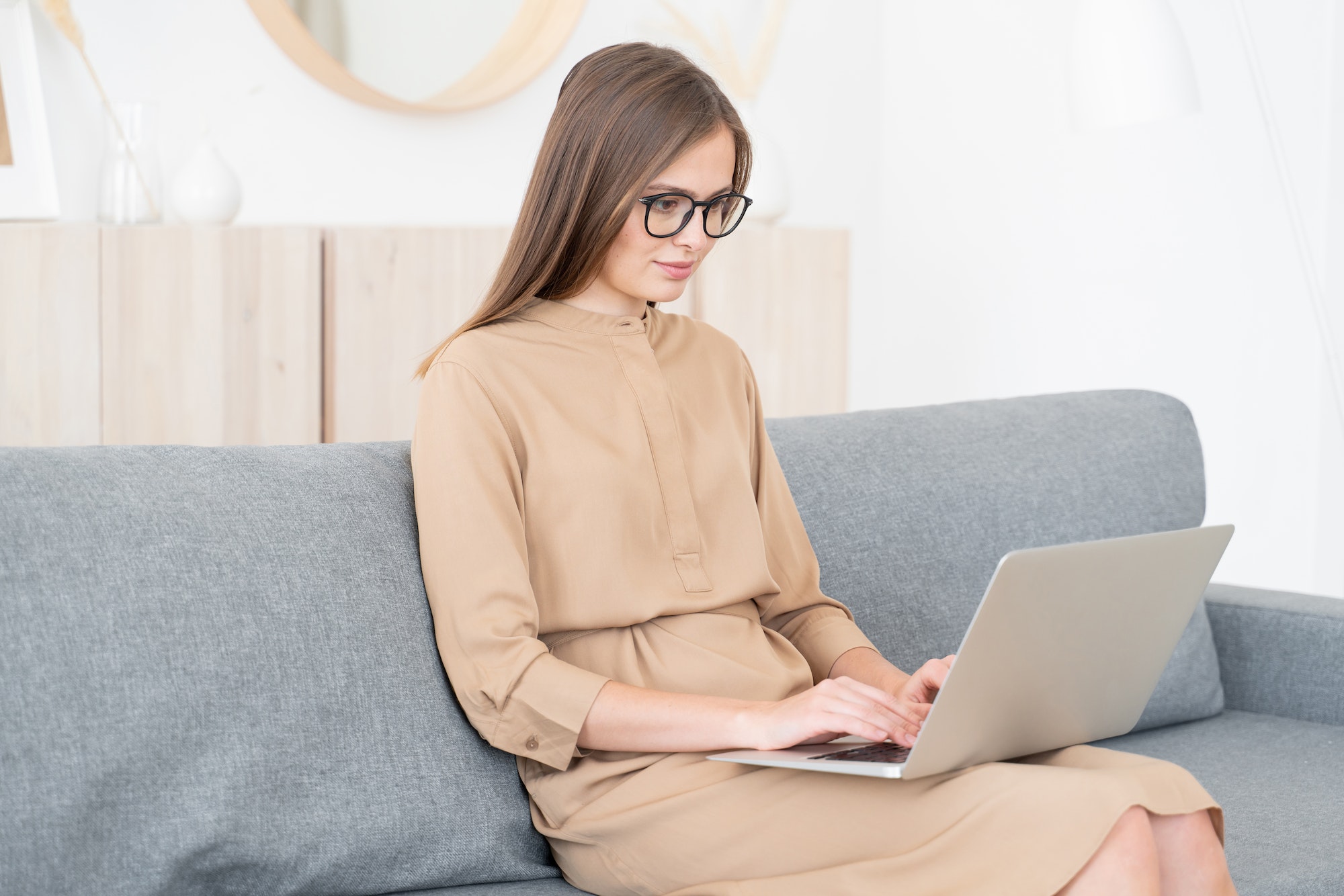 young-business-woman-sitting-on-sofa-with-open-laptop-working-from-home.jpg
